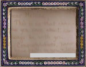 small blue picture frame with flowers around the border and a faded note behind the glass
