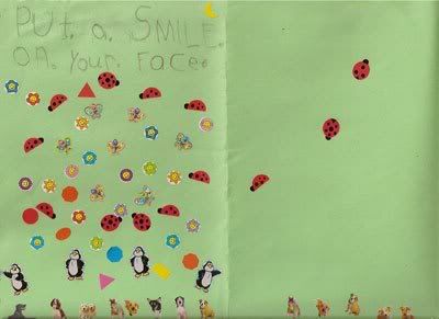 The outside of a card, made by a child, from green construction paper and stickers of dogs, penguins, shapes (triangles, squares, hearts, diamonds, circles), flowers, butterflies, ladybugs, and a yellow moon in the top right corner. The front says, in pencil, Put A Smile On Your Face.